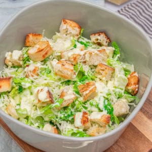 Frischer Caesar Salad mit Croutons und Dressing in einer großen Schale.