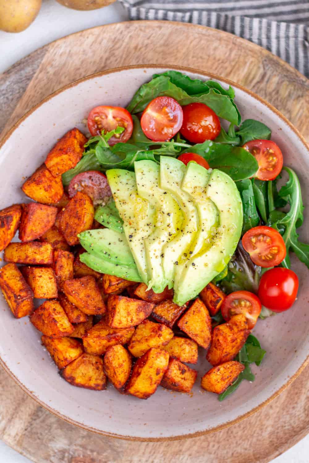 Einfaches Bowl Rezept mit knusprigen Kartoffeln aus dem Ofen und Avocado-Tomaten-Salat. Dazu passt mein schnelles selbstgemachtes Salatdressing mit Knoblauch.