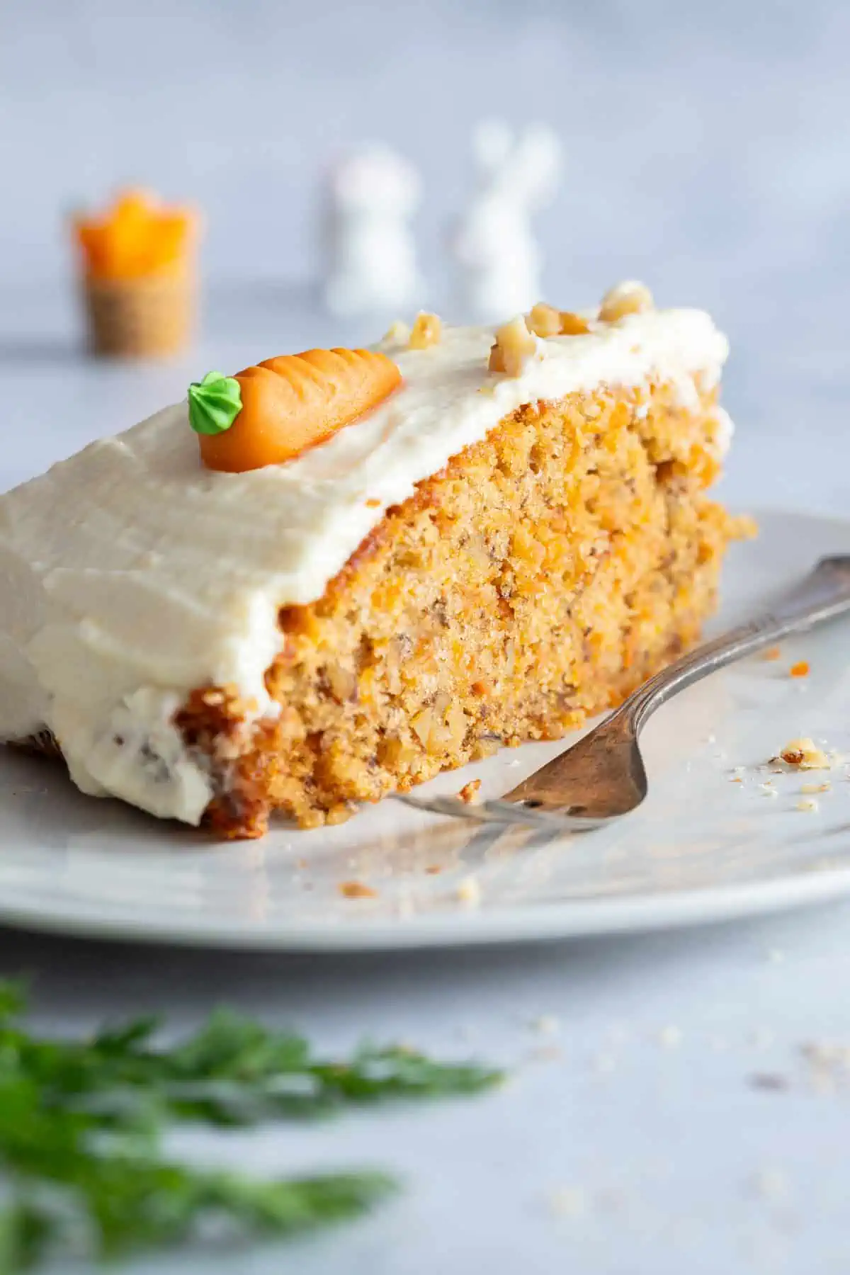 Ein Stück saftiger Karottenkuchen mit Frosting auf einem Teller serviert.