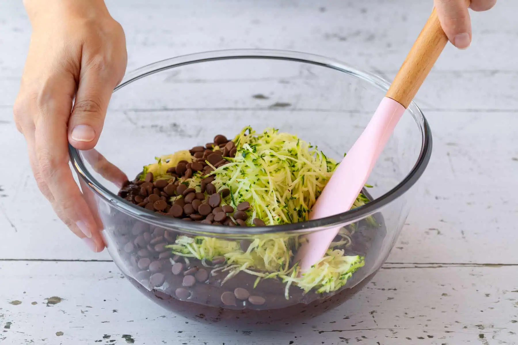 Geraspelte Zucchini und Schoko-Tröpfchen werden unter den Teig gemengt.
