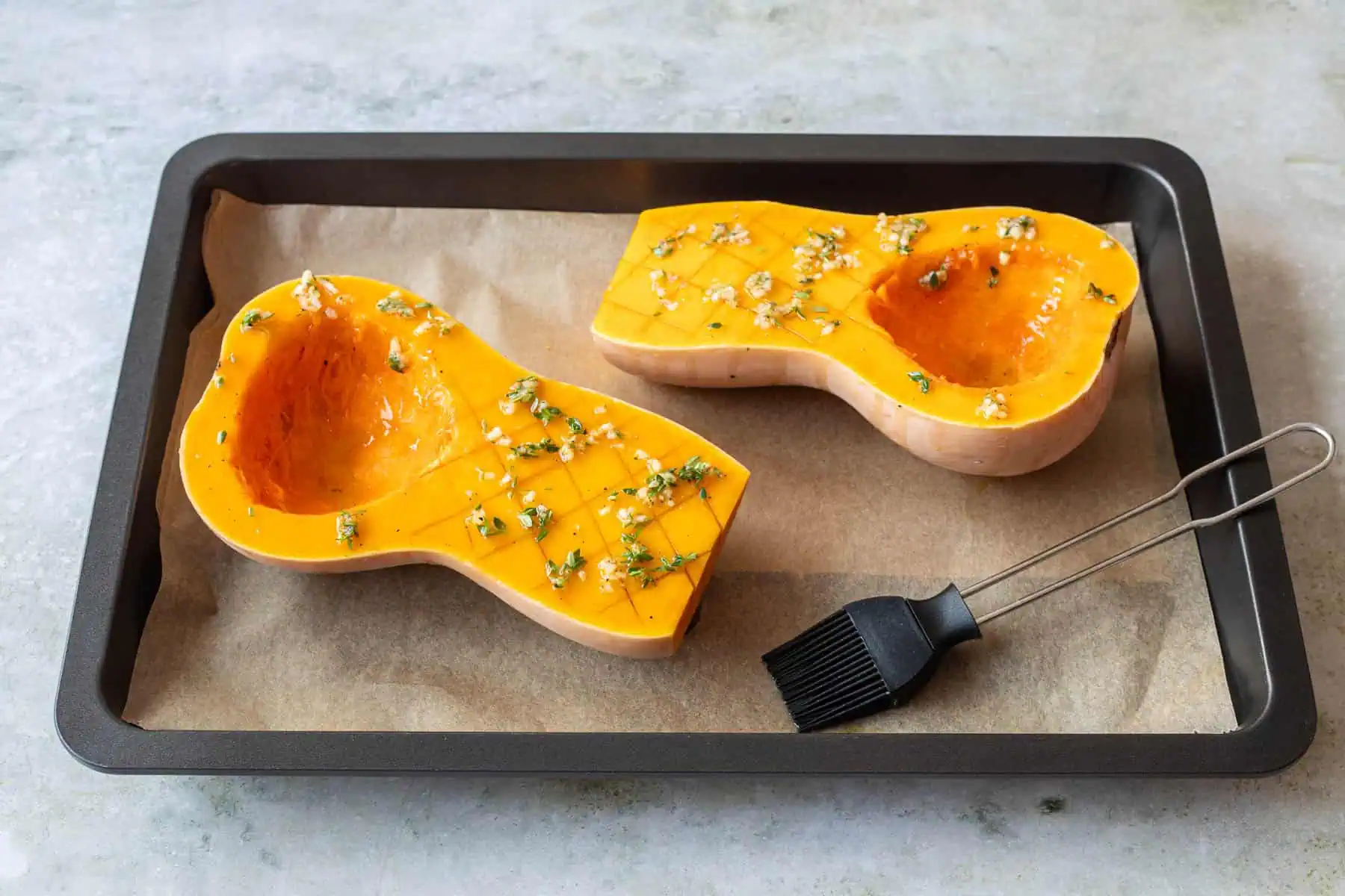 Butternut-Kürbis im Backofen zubereiten. Kürbis wird mit Olivenöl-Mischung bestrichen.