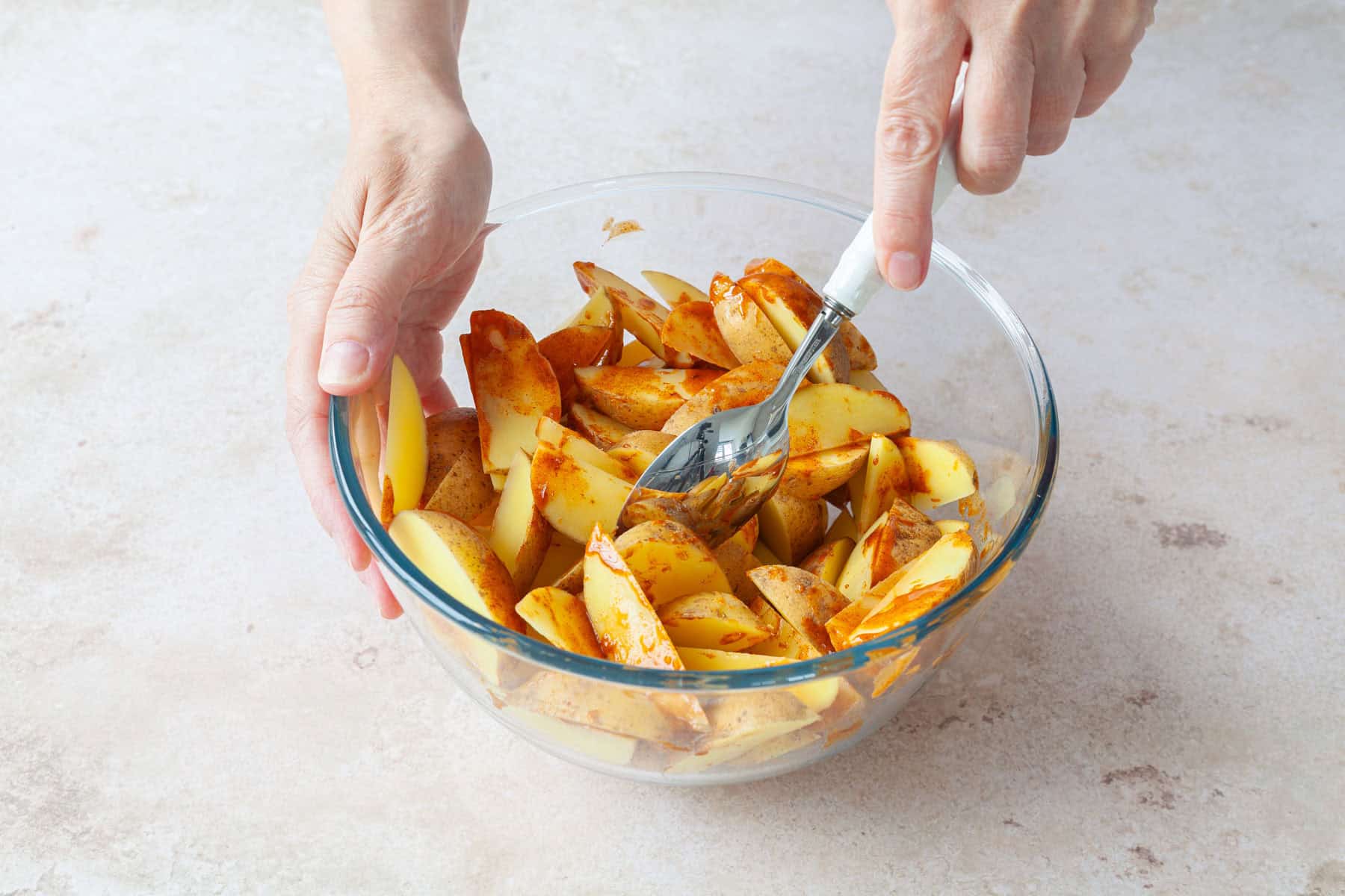 Kartoffelspalten werden in einer Schüssel mariniert