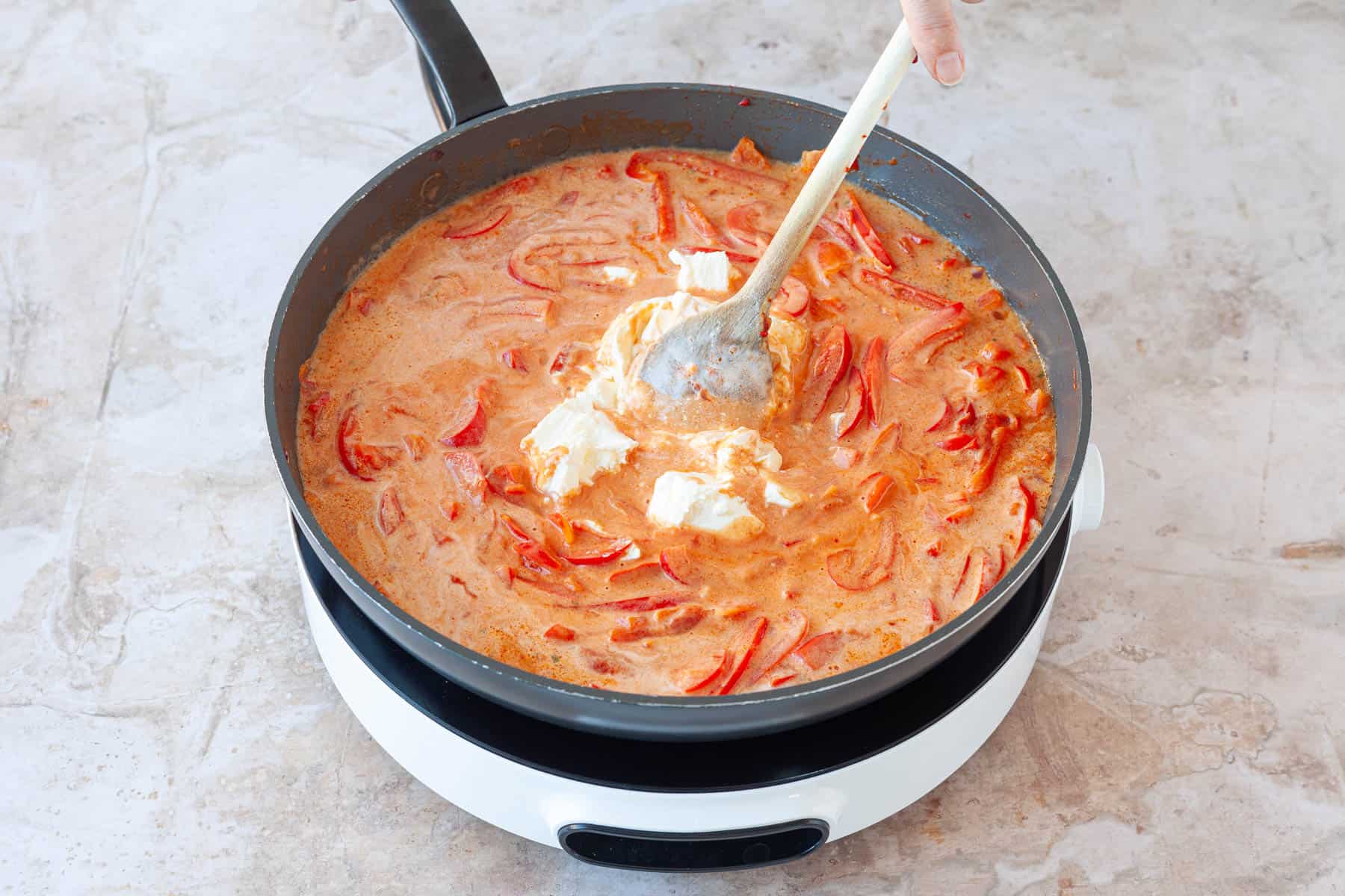 Frischkäse unter Paprika-Sahne-Soße rühren